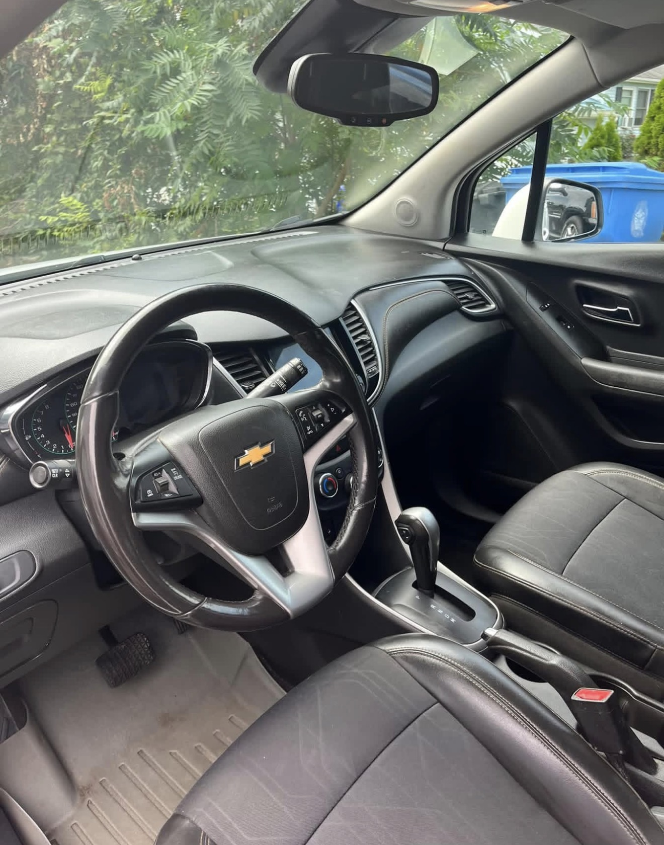 Interior of a Chevrolet SUV showing steering wheel, dashboard and black leather seats