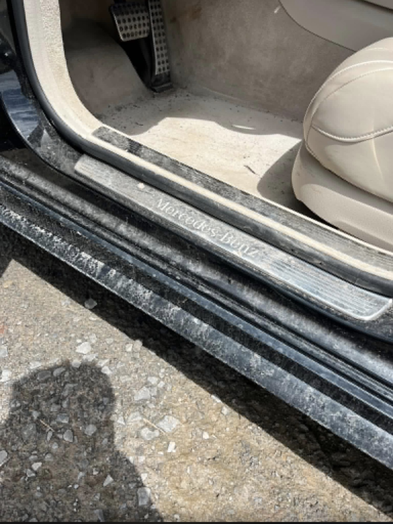 Dusty Mercedes-Benz door sill and beige interior with open driver's door