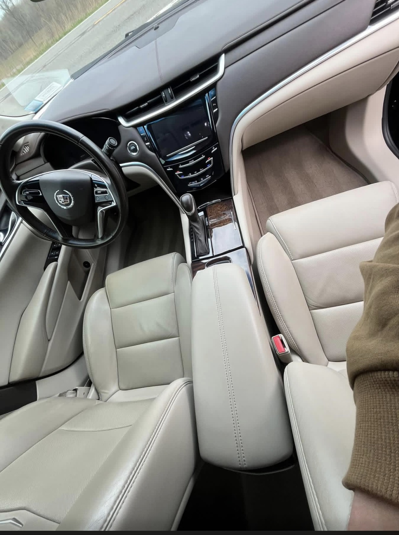 Cream leather interior of a Cadillac with steering wheel, touchscreen and front seats